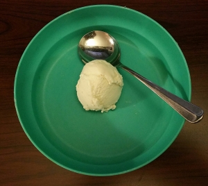 One scoop of vanilla ice cream in a teal bowl.